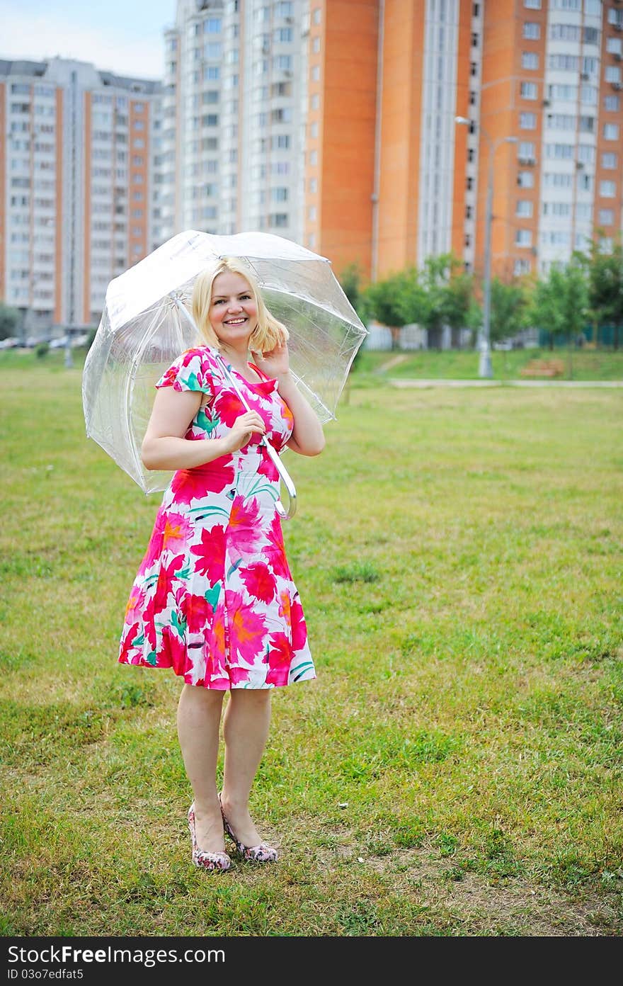 Adorable blond woman poses outdoors with umbrella