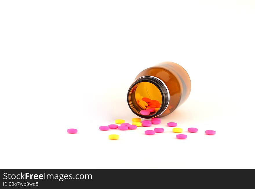 Yellow and pink pills spilling out of bottle (protect from ligh) isolated on white background. Yellow and pink pills spilling out of bottle (protect from ligh) isolated on white background