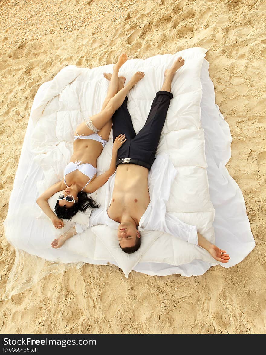 Beautiful young couple resting in bed in morning on the beach