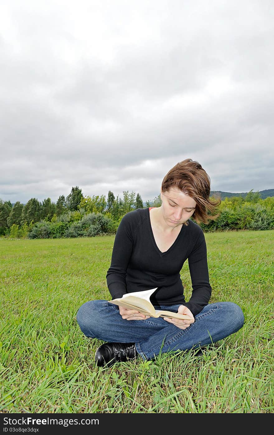 Young woman reading a book on the meadow. Young woman reading a book on the meadow