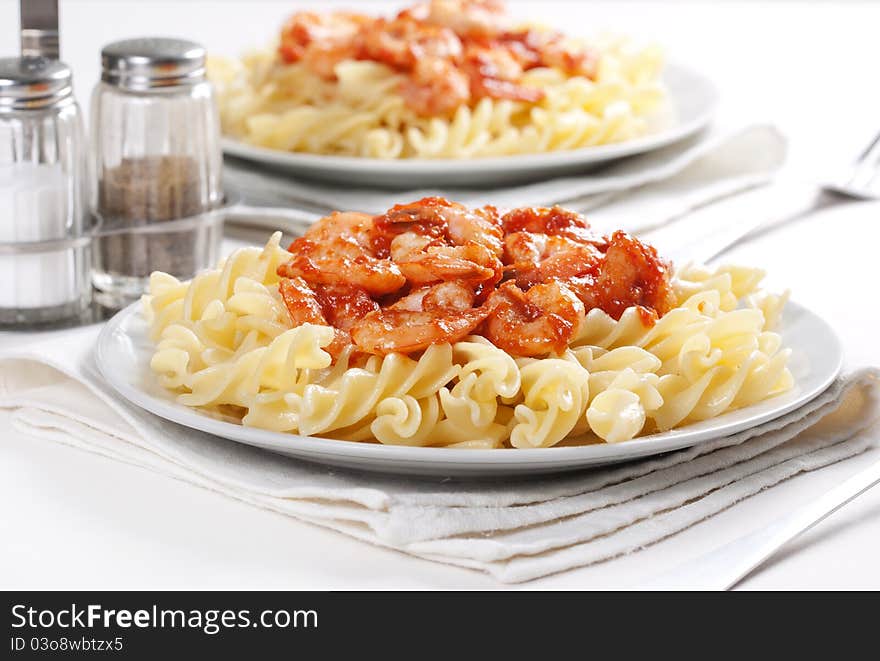 Two plates of pasta with tomato and shrimps