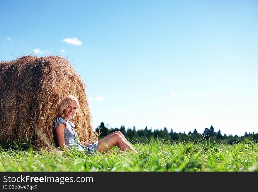 Portrait of a girl next to a stack of hay under the blue sky