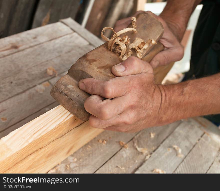 Hands of a carpenter planed wood, workplace