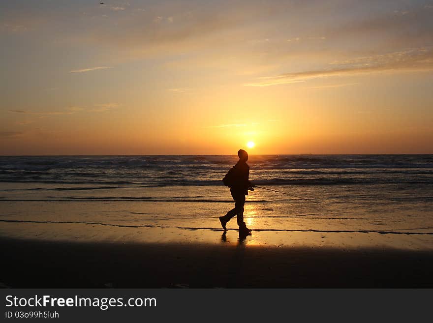 Fisherman walking by during sunset at Ocean Beach in San Francisco. Fisherman walking by during sunset at Ocean Beach in San Francisco