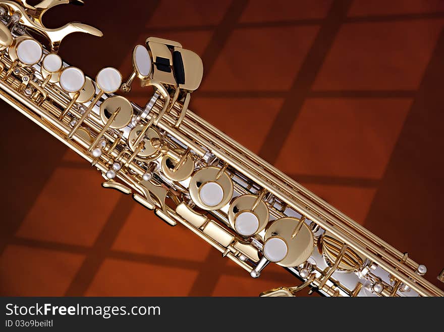 A professional silver and gold soprano saxophone isolated on a window shadow. A professional silver and gold soprano saxophone isolated on a window shadow.