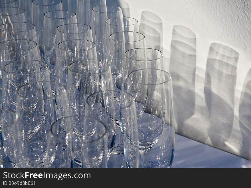 Empty wine glasses organized in rows trowing shadows on the wall. Empty wine glasses organized in rows trowing shadows on the wall.