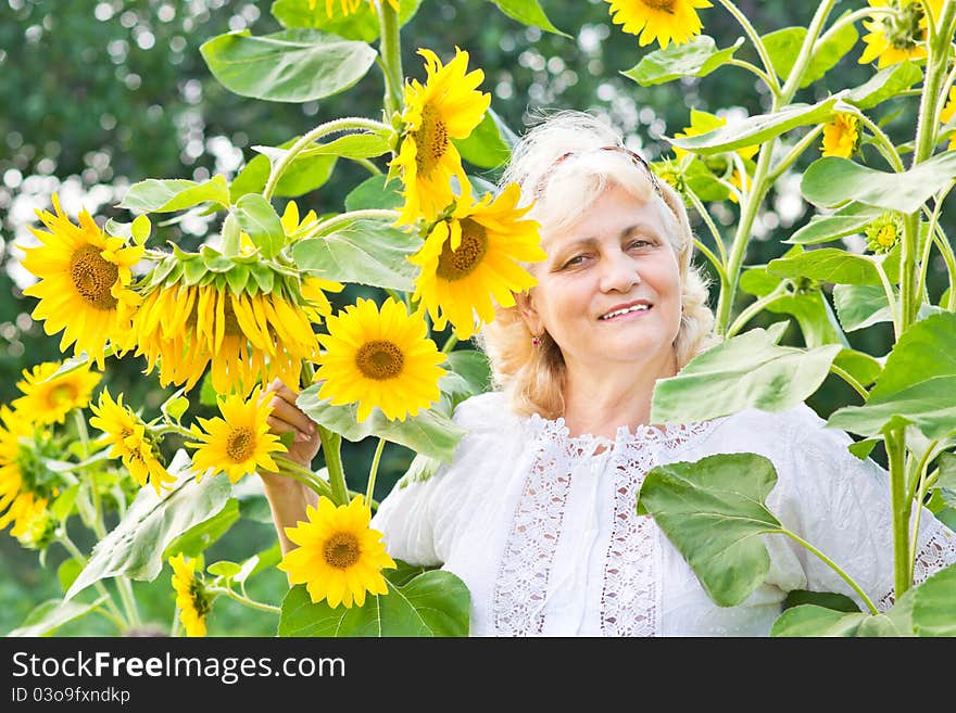 Happy woman with sunflowers in her garden