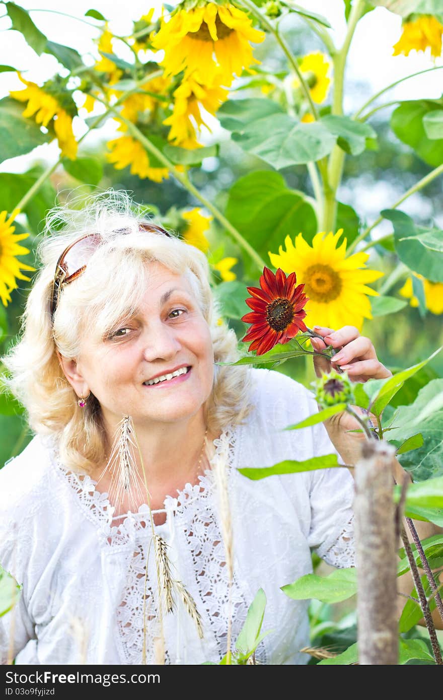 Gardening in summer - happy woman with flowers in her garden