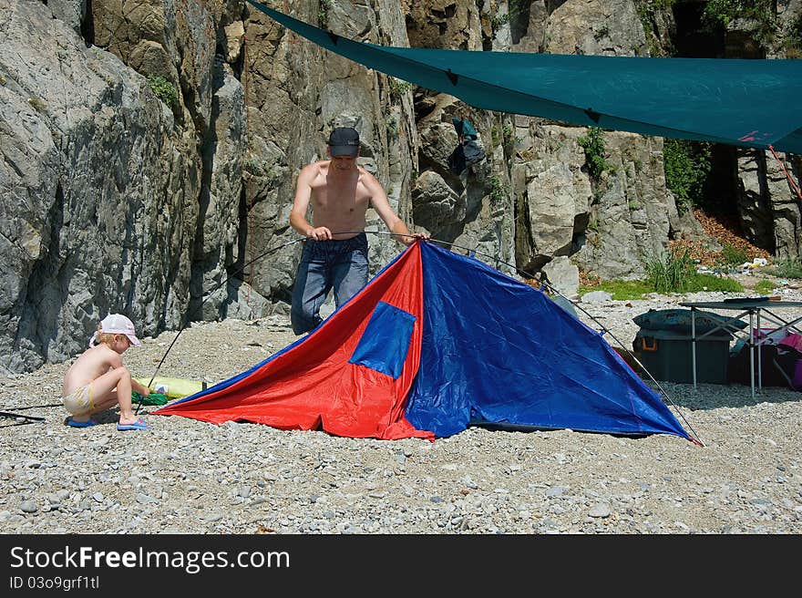 Father and daughter put a tent next to the rocks. Father and daughter put a tent next to the rocks