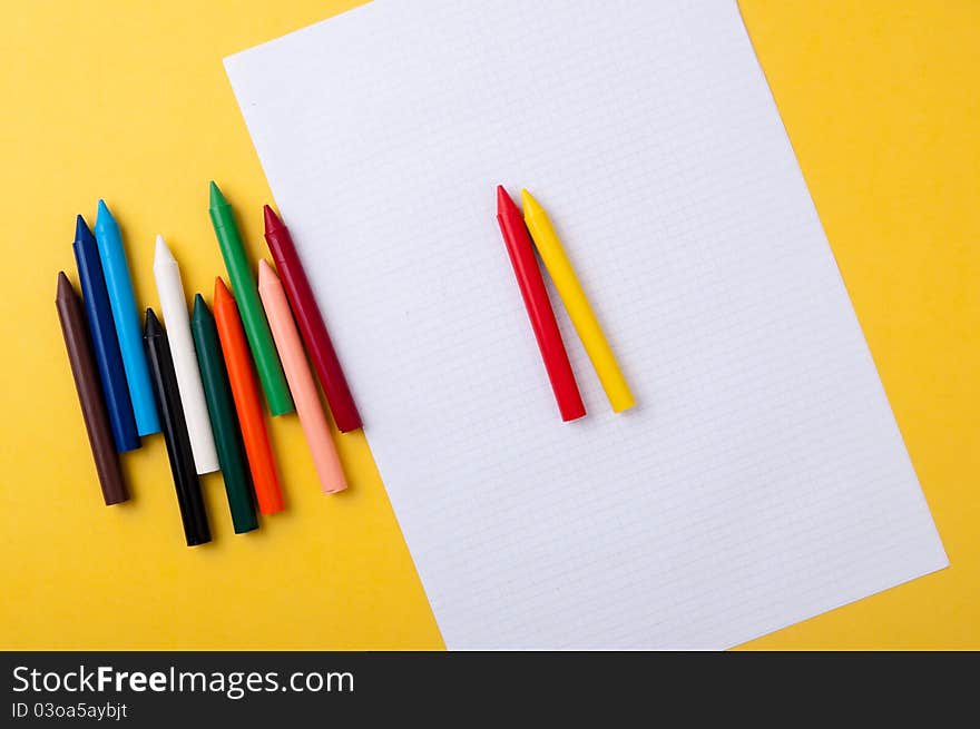 Drawing paper and crayons colored yellow background