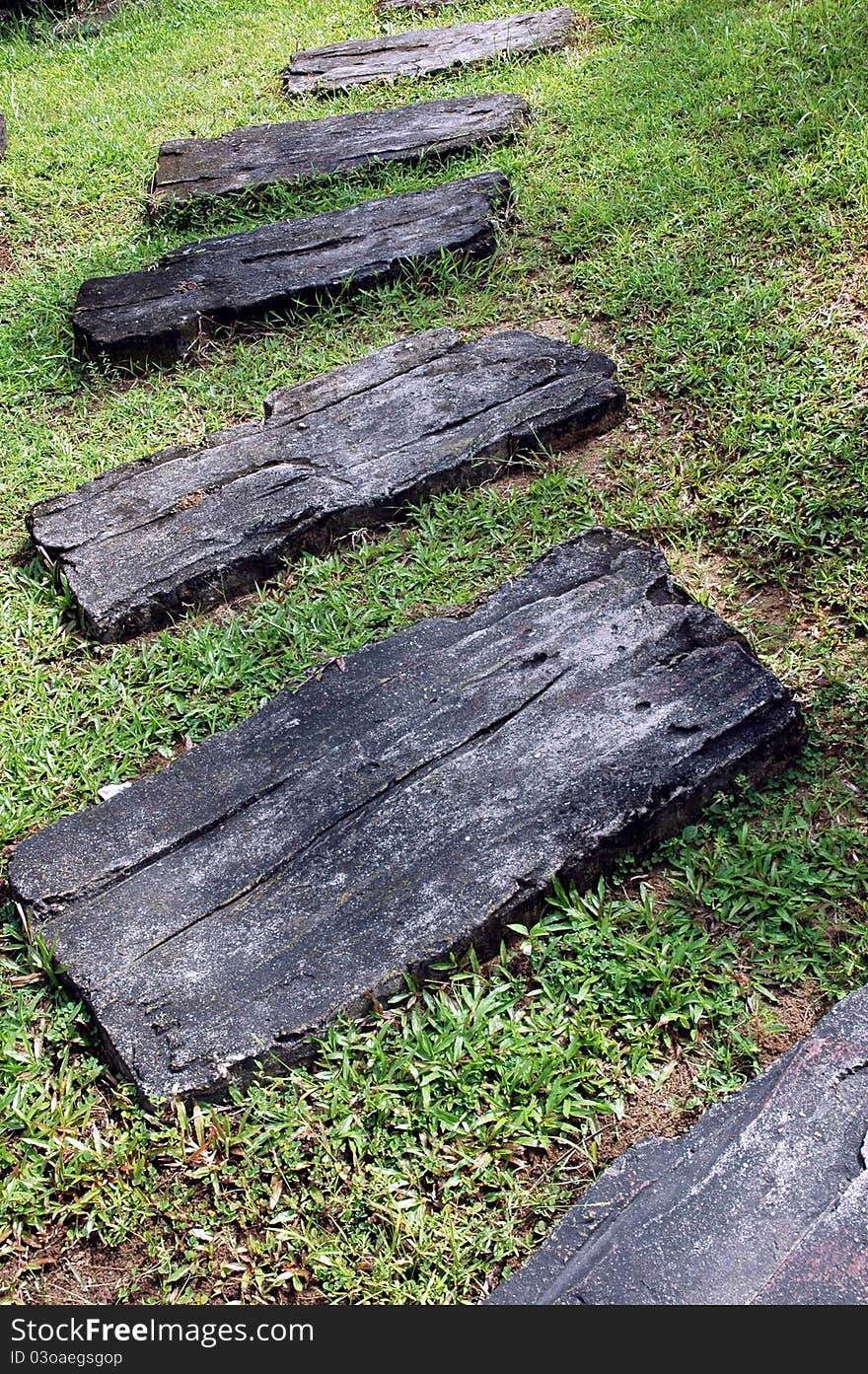 A curvaceous foothpath made of concrete blocks across the grass