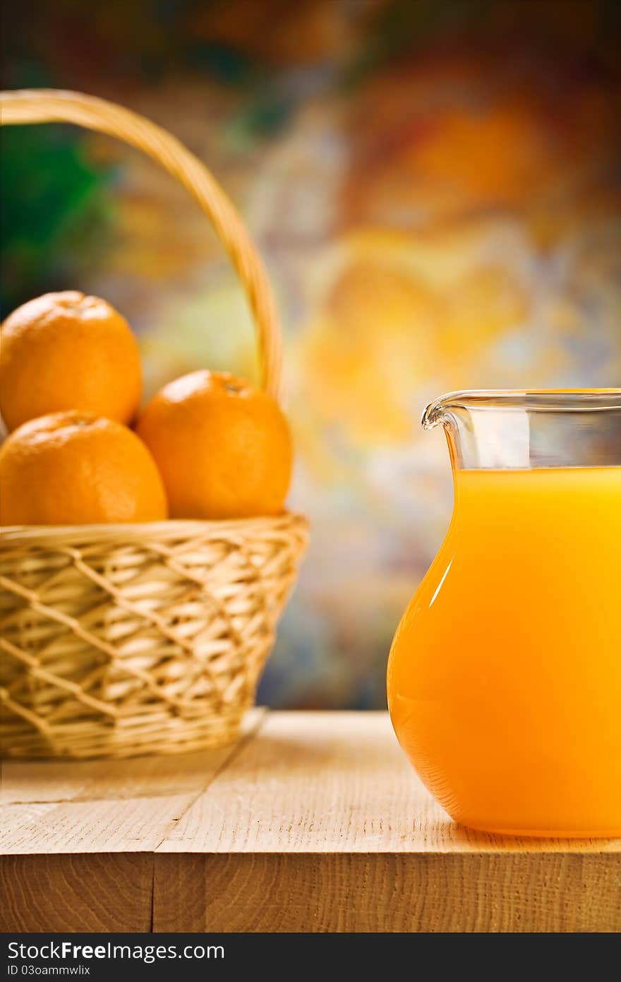 Studio shot 
jug with orange juice and oranges in busket on wooden boards