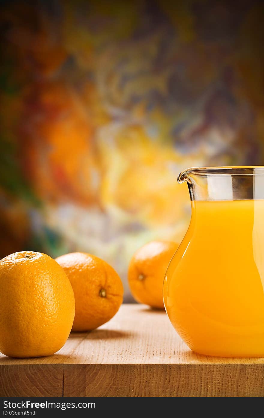 Orange juice in glass jug and oranges on wooden boards. Orange juice in glass jug and oranges on wooden boards