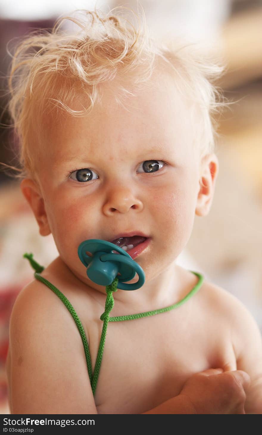 Lentny portrait of the little girl of the blonde (1 year) with a green dummy. Lentny portrait of the little girl of the blonde (1 year) with a green dummy