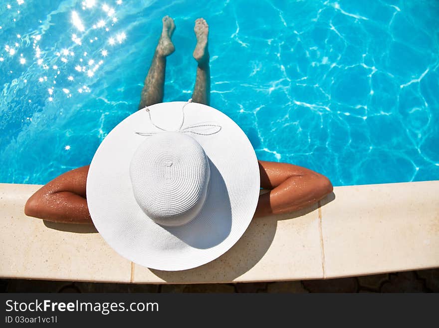 Young woman sitting near pool.