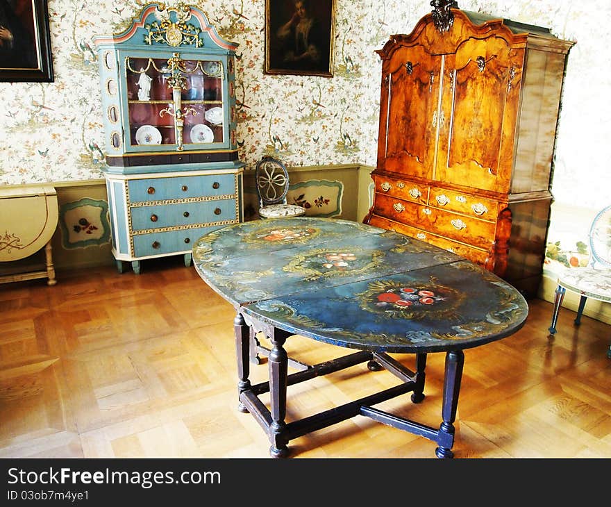 Vintage dining room: an old table, wardrobe, commode and retro wallpaper on walls