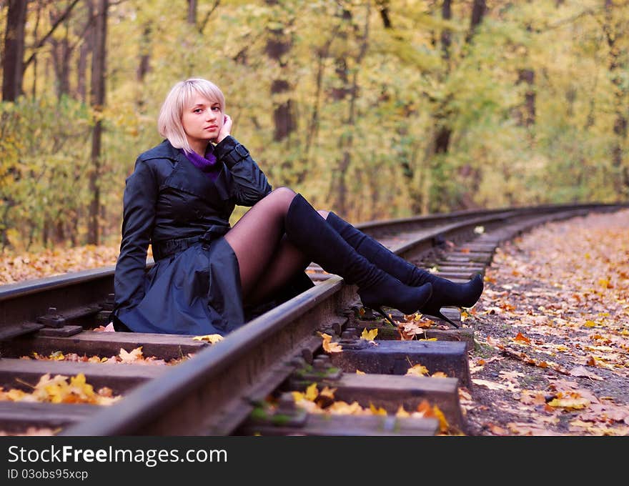 Young beautiful girl posing on rails in autumn scenery. Concept of an autumn mood. Young beautiful girl posing on rails in autumn scenery. Concept of an autumn mood.