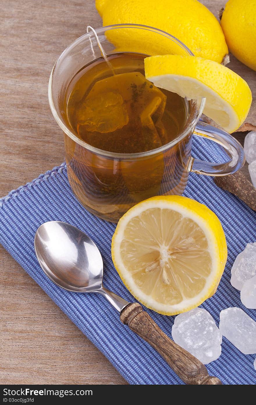 Studio-shot of a glass with fresh hot lemon tea, a slice of lemon, rock sugar and a cinnamon stick.