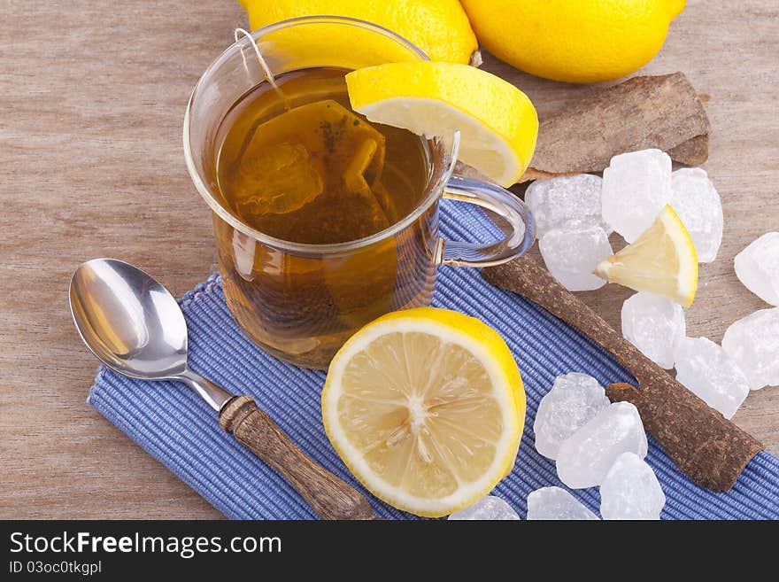 Studio-shot of a glass with fresh hot lemon tea, a slice of lemon, rock sugar and a cinnamon stick.