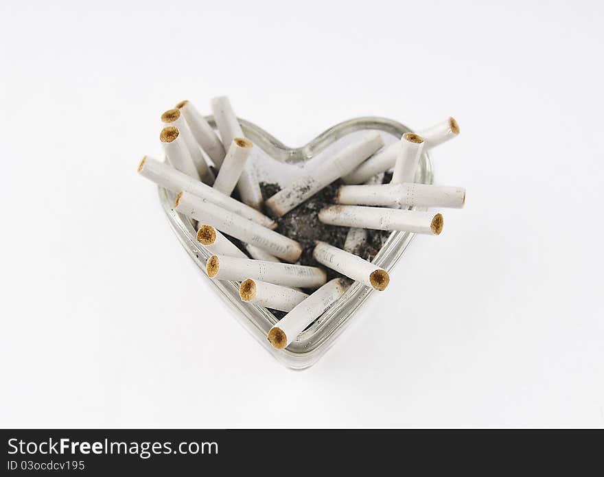 Glass heart with cigarette butts on a white background