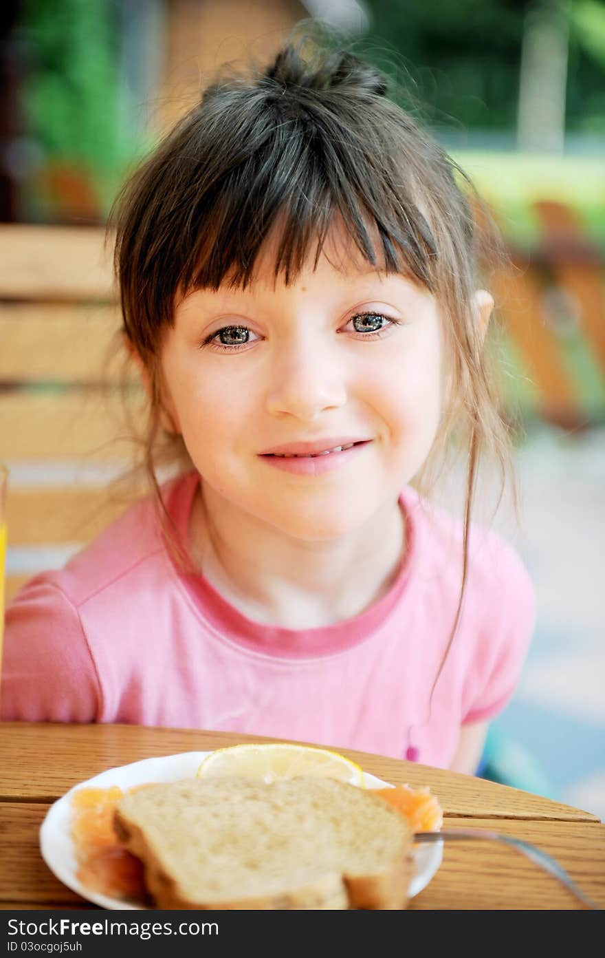 Cute child girl with tumbled hair has breakfast outdoors. Cute child girl with tumbled hair has breakfast outdoors