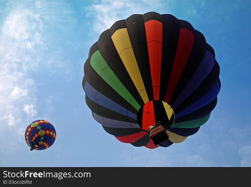 Two hot air balloons launching against a bright blue sky. Two hot air balloons launching against a bright blue sky