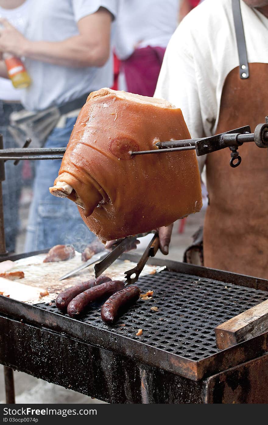 A man is barbecuing piece of pork meat and sausages. A man is barbecuing piece of pork meat and sausages.