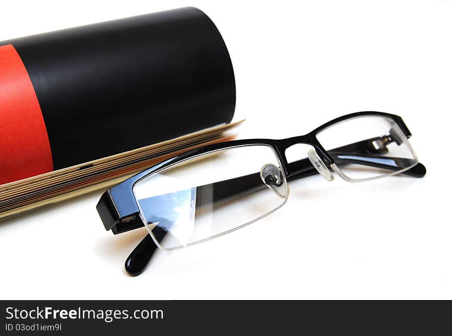 Black and red colored magazine with glasses in front over white background