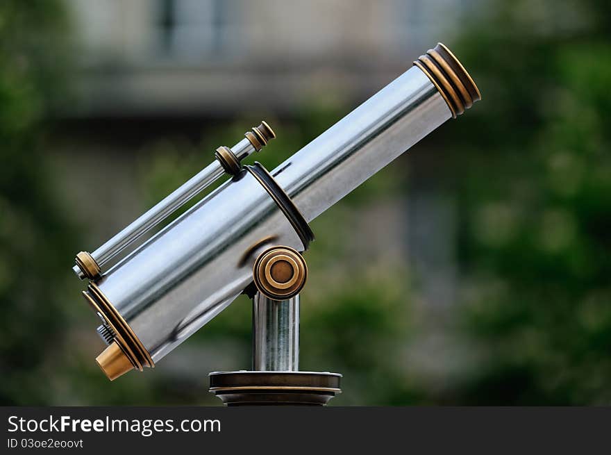 An tourist type telescope against the green trees. An tourist type telescope against the green trees