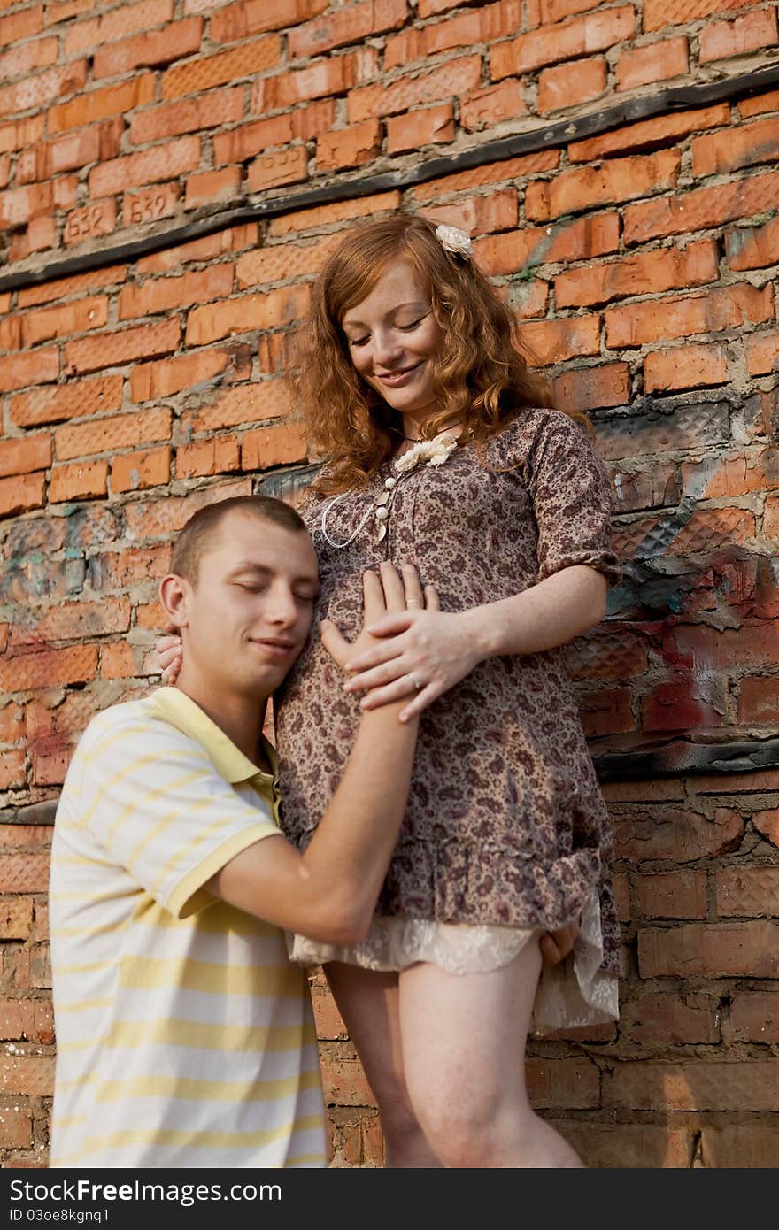 Portrait of a happy young man kisses his pregnant wife . outdoor .