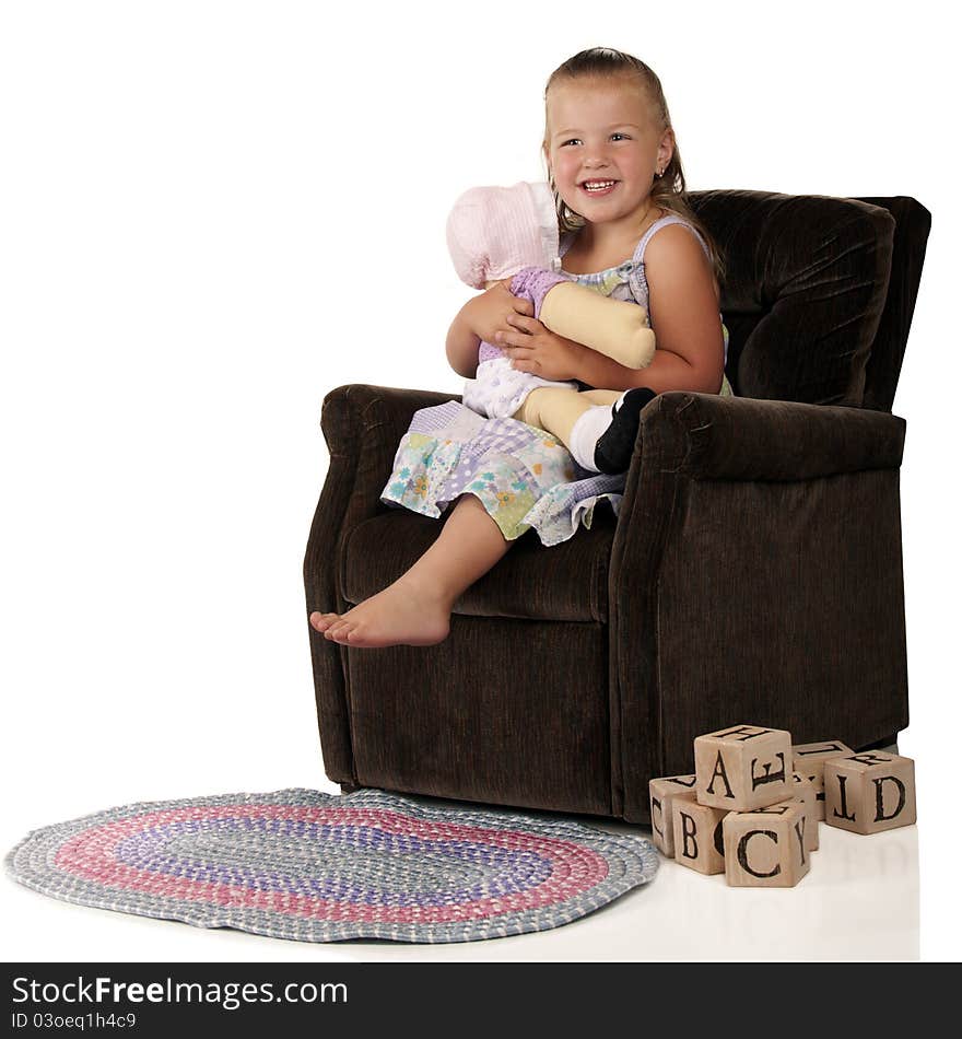 An adorable preschooler hugging her doll while sitting in a child-sized plush chair. A braided rug and pile of alphabet blocks are on the floor nearby. An adorable preschooler hugging her doll while sitting in a child-sized plush chair. A braided rug and pile of alphabet blocks are on the floor nearby.