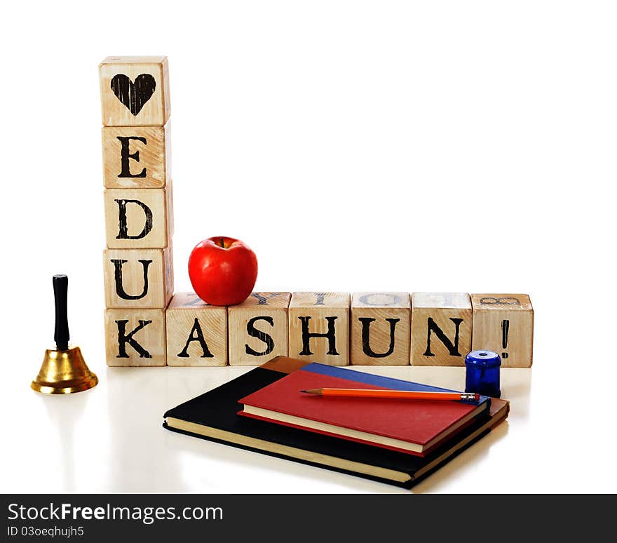 Rustic alphabet blocks spelling out the message, Love Edukashun with a shcool bell, apple, and study supplies nearby. on white. Rustic alphabet blocks spelling out the message, Love Edukashun with a shcool bell, apple, and study supplies nearby. on white.