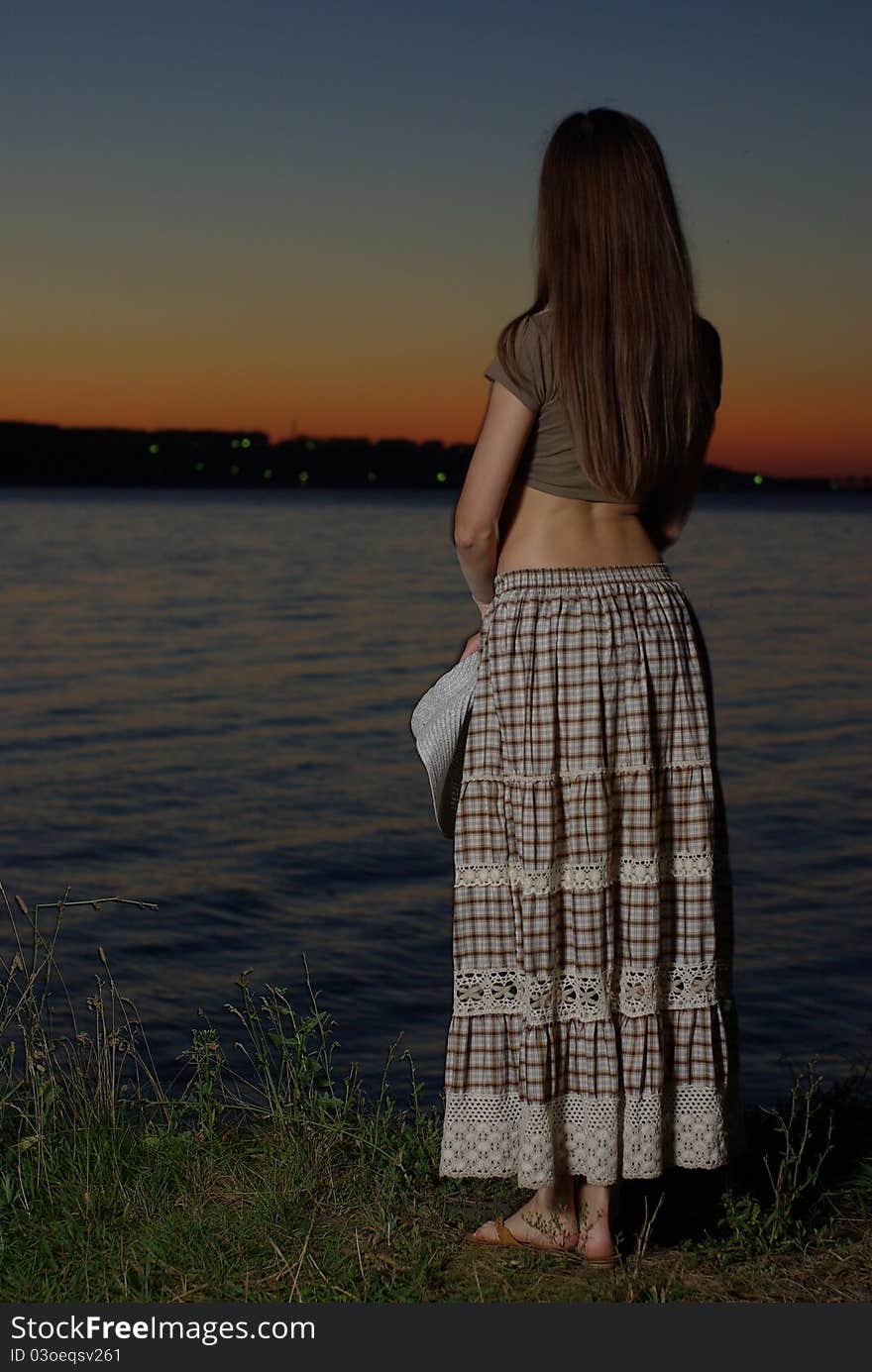 Female standing by the water in the twilight. Female standing by the water in the twilight