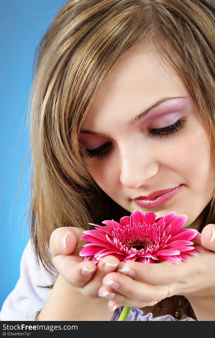 Attractive smiling woman portrait with flower in her hand on blue background