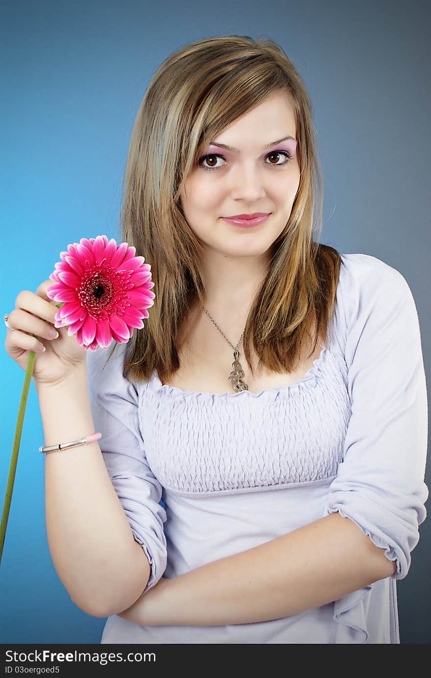 Attractive smiling woman portrait with flower in her hand on blue background