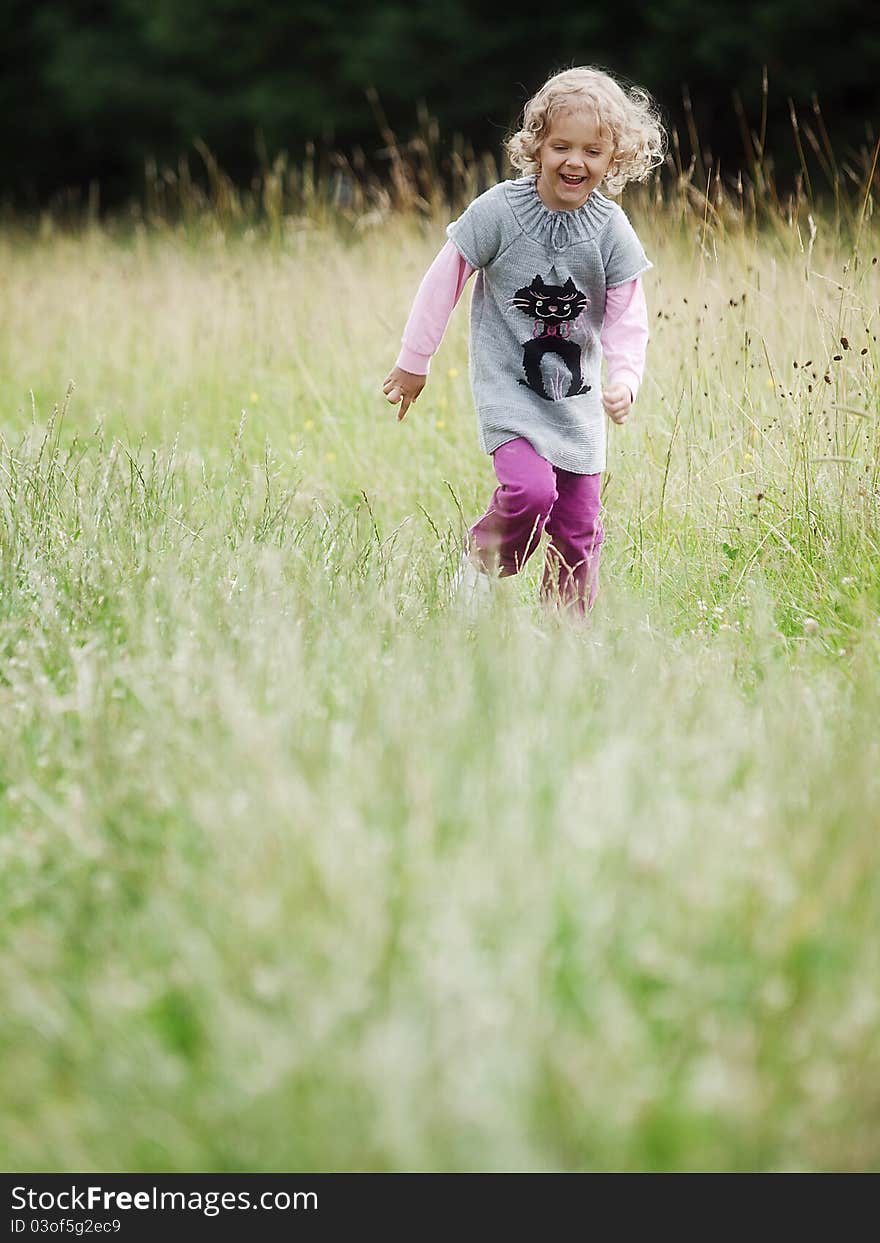 Running little girl across a meadow