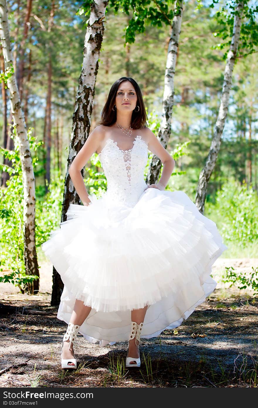 Bride with dark-brown hair posing in forest