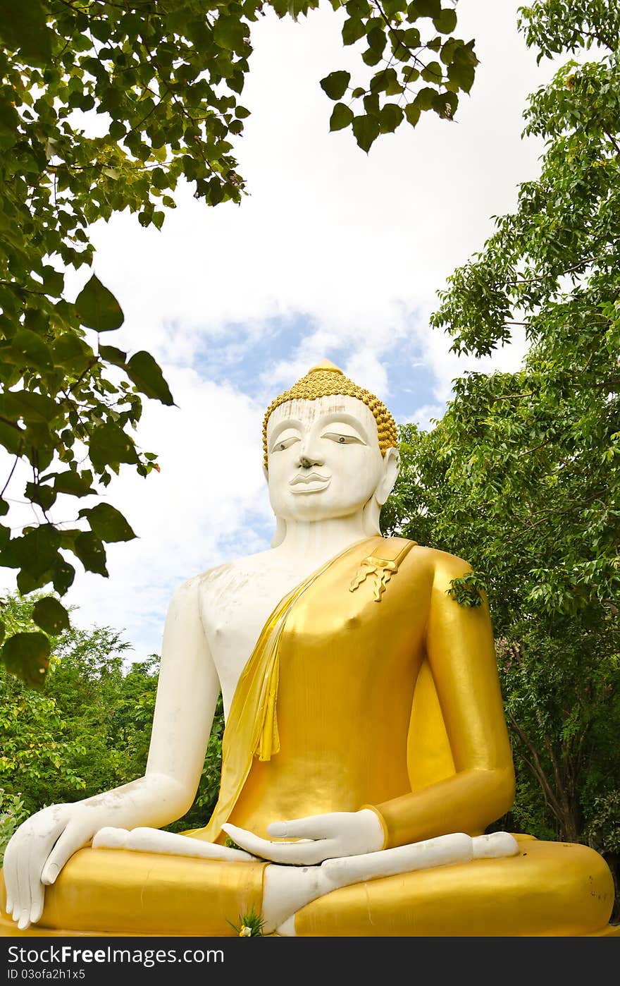 White & yellow sitting Budha image with blue sky