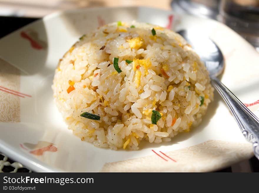 Round Chinese Fried Rice Served on a Dish with a Spoon Aside. This is a Japanese version of Chinese Fried Rice commonly served at most Ramen restaurants in Japan.