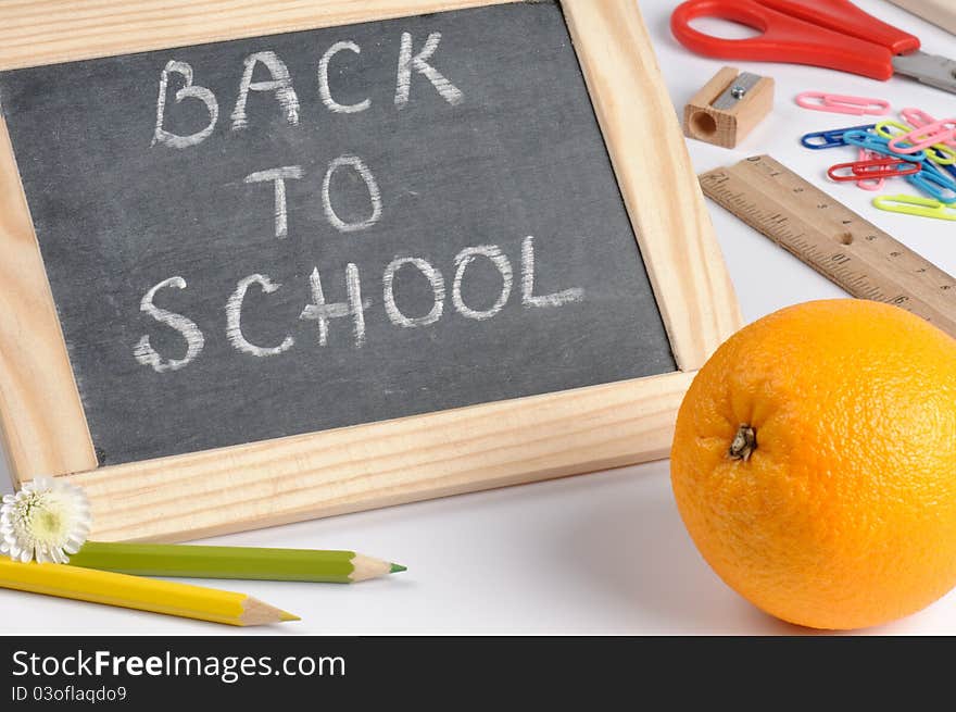 Back to school composition with blackboard and orange