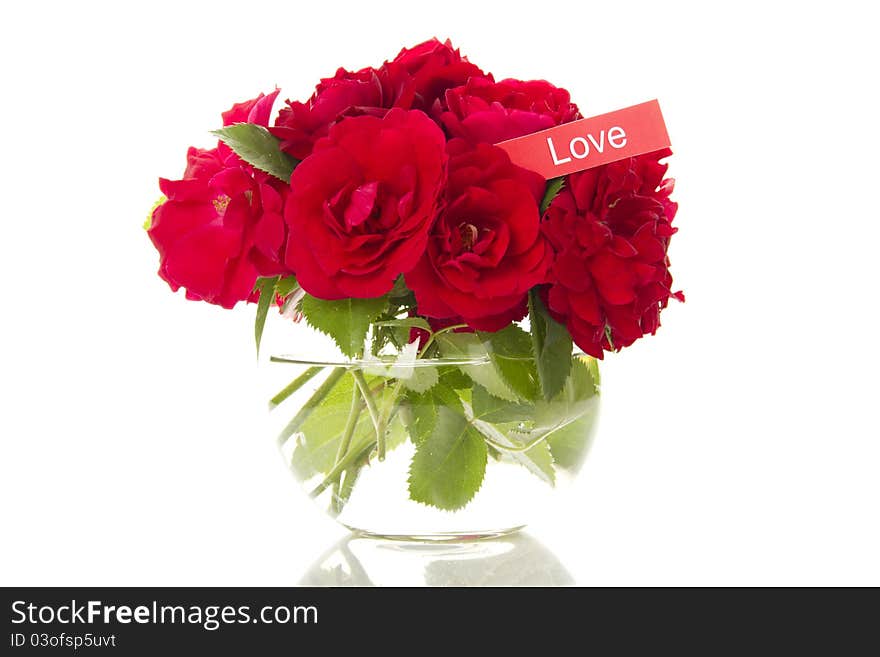 Close-up of a beautiful bouquet of red roses in a round glass vase. Isolated