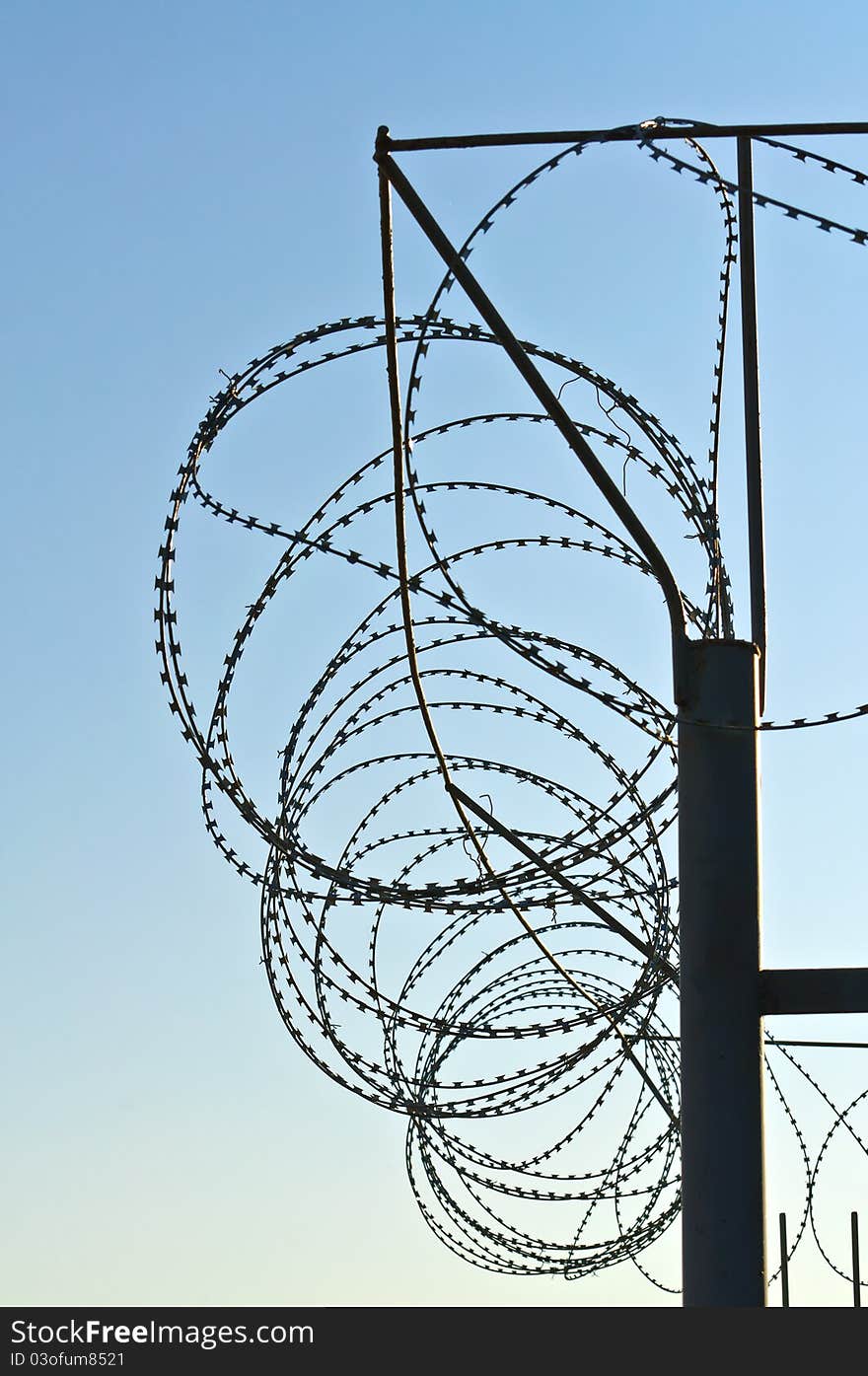 Fence of barbed wire. Against the blue sky