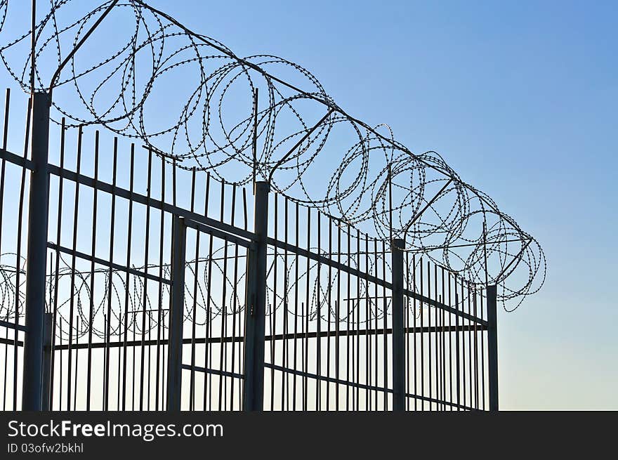 Fence of barbed wire. Against the blue sky