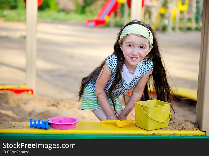 Happy child girl is playing in a sandbox