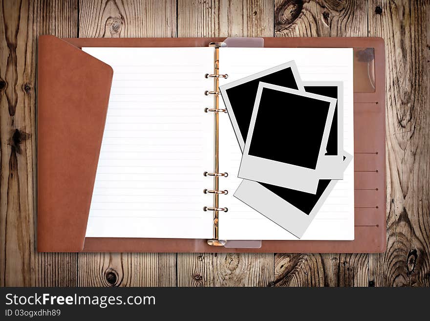 Blank photo and notebook on wooden background