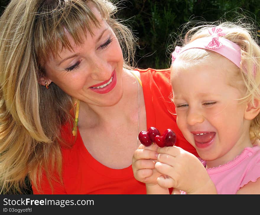 Mother with little daughter looks at unusual cherries. Mother with little daughter looks at unusual cherries