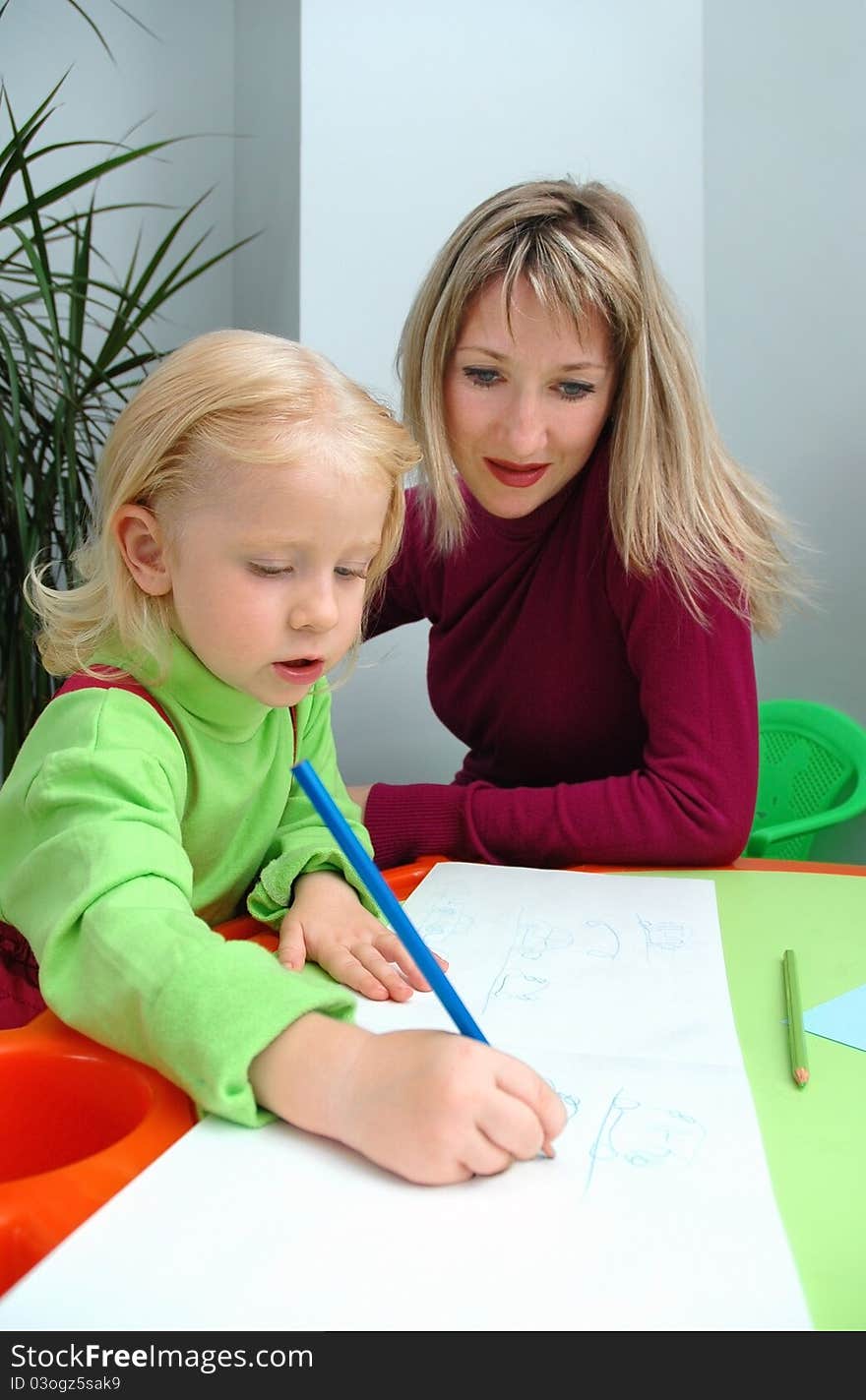 Little girl with mother draws pencil