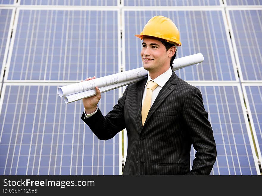 Male engineer at solar power station holding blueprints.