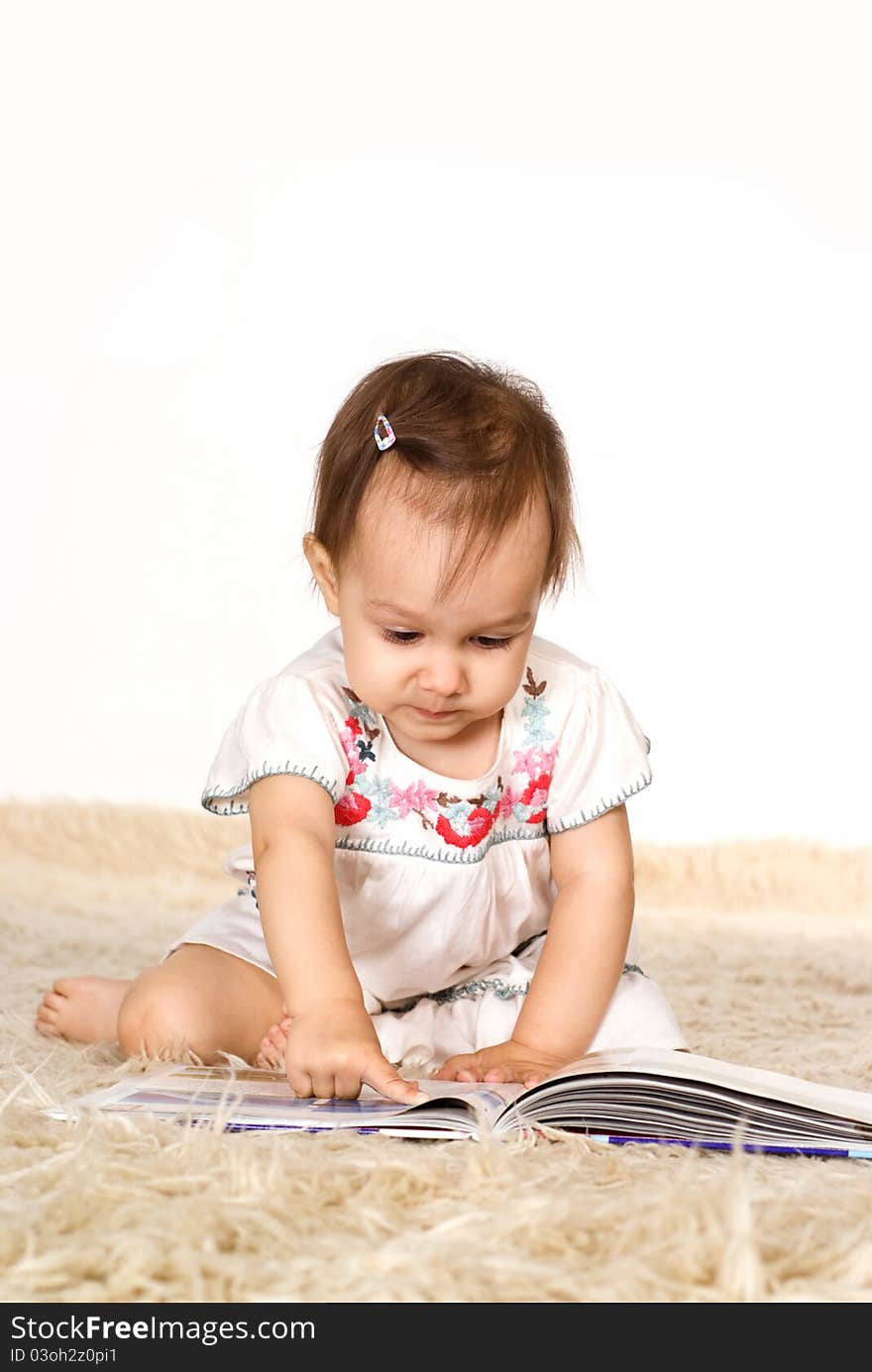 Little girl reading a book on a carpet