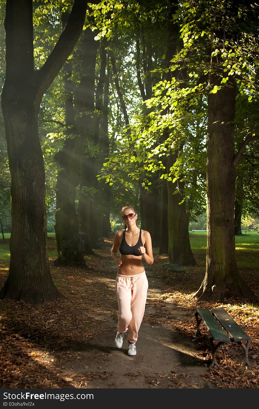 Attractive young woman jogging in the part at sunset or sunrise. Attractive young woman jogging in the part at sunset or sunrise